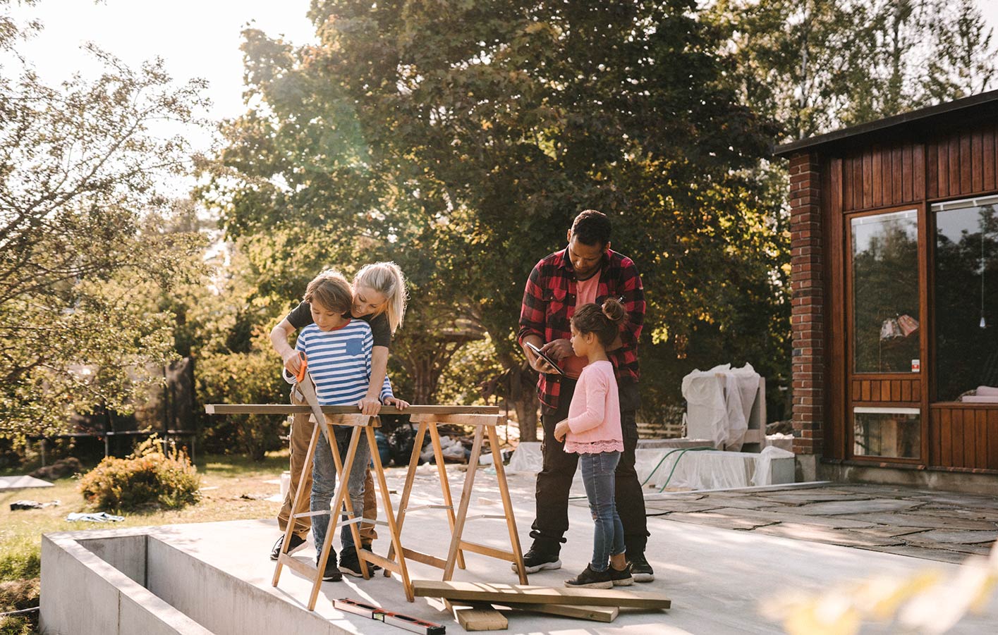 Familie baut gemeinsam im Garten mit Holz